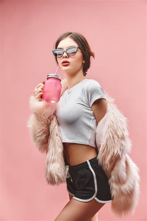 Girl In Faux Pink Fur Coat Black Shorts White Top And Sunglasses Holds