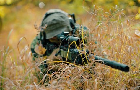 Airsoft Man In Uniform Lay In Long Grass With Sniper Rifle Soldier Aims At The Sight Stock