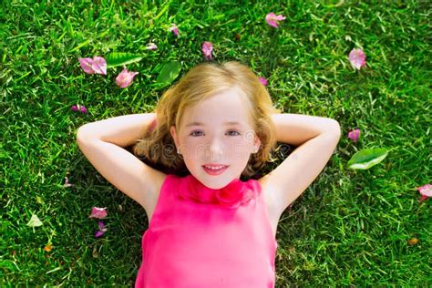 Blond Kid Girl Lying On Garden Grass Smiling Aerial View Stock Image