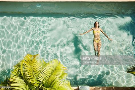 Overhead View Of Woman Floating On Her Back In Pool At Outdoor Spa