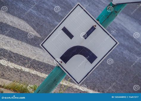 A Road Sign Beside The Street Resembling An Angry Face Stock Image