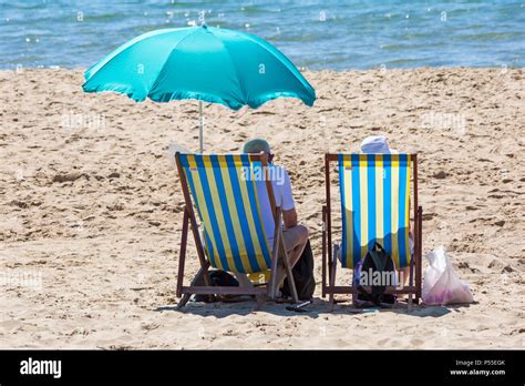 Couple Sitting In Deckchairs On The Beach Hi Res Stock Photography And