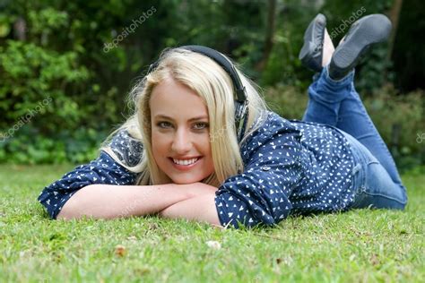 Pretty Blond Girl Lying On Grass With Earphones Stock Photo
