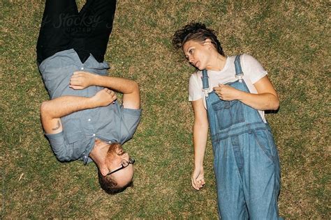adventurous couple laying in grass after getting wet fully clothed in pool water by jesse morrow
