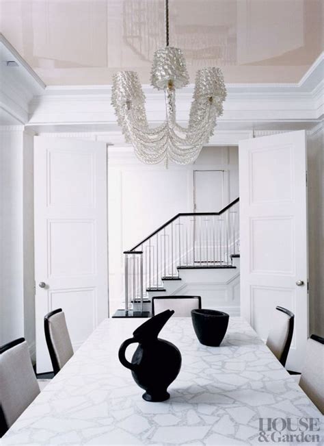 In this small apartment, the dining area has a deep teal blue accent wall that ties in with the front door and storage closet, while the wood furniture adds a natural touch and the black chairs match the black framed glass wall of the bedroom. High gloss ceiling with touches of graphic black and white ...