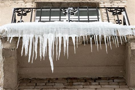 Premium Photo Large Icicles Hang From The Roof Of The Building And