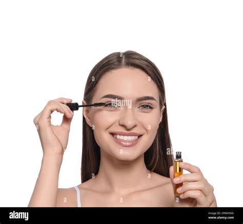 Young Woman Applying Oil Onto Her Eyelashes On White Background Stock