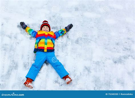 Little Kid Boy Making Snow Angel In Winter Outdoors Stock Photo