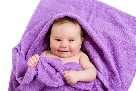 Newborn Baby Lying Down And Smiling In A Purple Towel Stock Photo