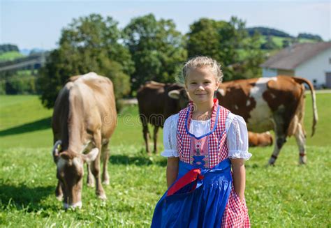 Прелестная маленькая баварская девушка на поле страны с коровой в ge Стоковое Изображение