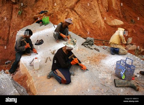 Two Workers With Splitter On Hand Try To Split Large Rock Into Small