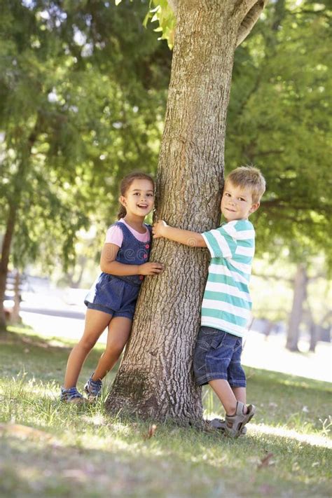 Dos Niños Que Abrazan El árbol En Parque Foto De Archivo Imagen De