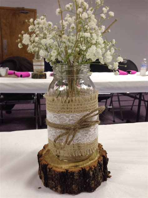 A Vase Filled With White Flowers Sitting On Top Of A Wooden Stump Next To A Table