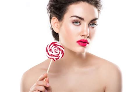 Attraktive junge nackte Frau isst roten Lutscher isoliert auf weiß