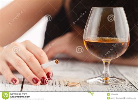 drunk woman holding an alcoholic drink and sleeping with her head on the table focused on the