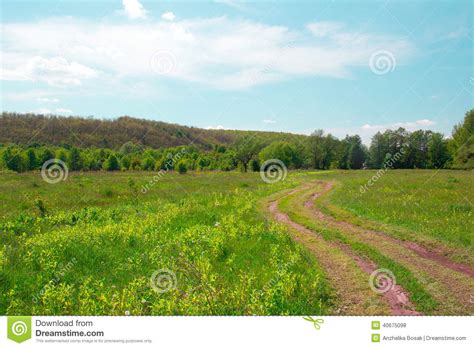Landscape Of A Green Grassy Valley With Footpath Trees Hills A Stock