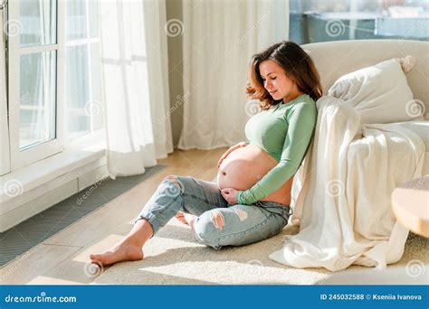 Cute Young Pregnant Brunette Woman In Modern Clothes In White Room The