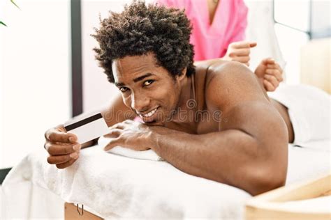 Young African American Man Having Massage Holding Credit Card At Beauty