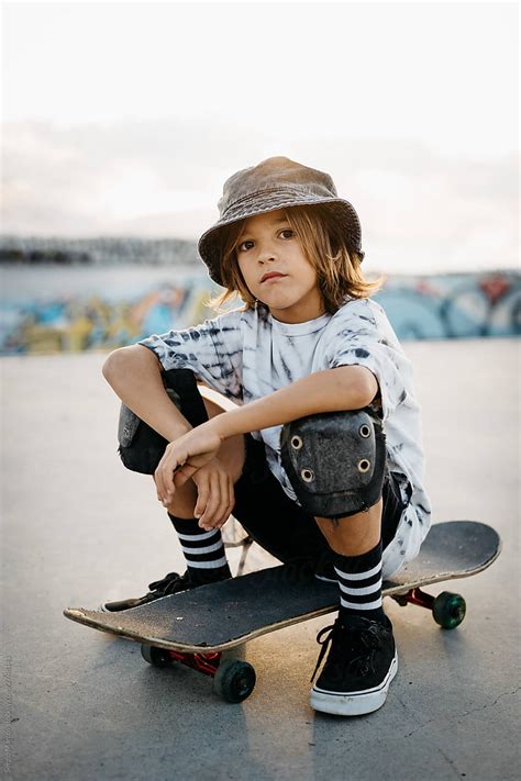 Portrait Of Skater Kid Sitting On His Skateboard At Sunset Del