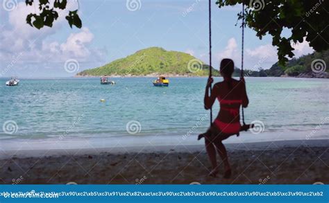 A Young Girl In A Bathing Suit Swinging On A Homemade Rope Swing On A