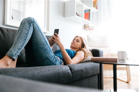 Darum bieten wir unsere sofas, sessel und couchlandschaften zu günstigen preisen an. Frau, die auf sofa liegt und handy zu hause benutzt ...