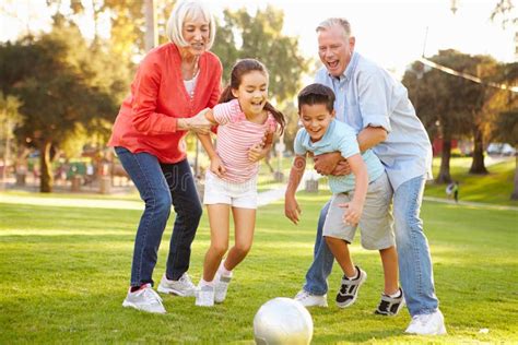 Grands Parents Jouant Le Football Avec Des Petits Enfants En Parc Photo