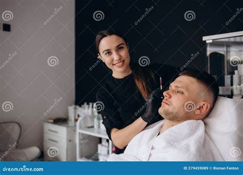 Female Beautician Giving Male Patient Botox Injection In A Forehead