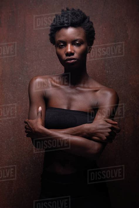 sensual african american female wearing tight black top with bare shoulders standing with arms