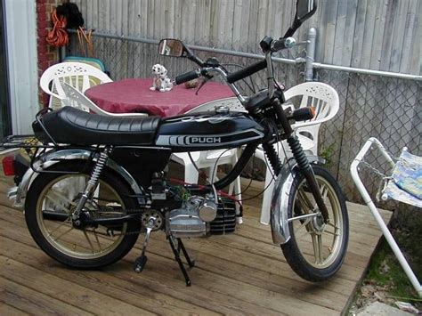 A Black Motorcycle Parked On Top Of A Wooden Deck Next To A White Chair