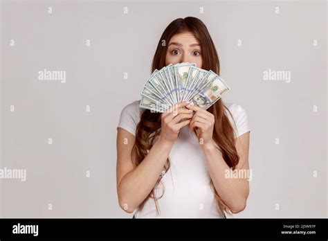 Amazed Happy Woman With Brown Hair Hiding Face Behind Fan Of Dollars