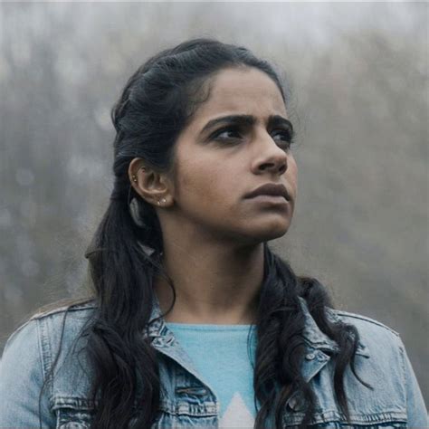 A Woman With Long Black Hair Wearing A Denim Jacket And Looking Off Into The Distance