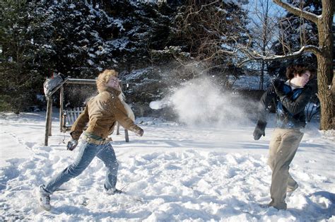 Playful Man Throwing Snowball On Brother In Backyard Stock Photo