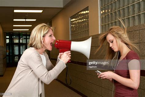 Woman Yelling Through A Bullhorn At An Unfazed Teenage Girl High Res