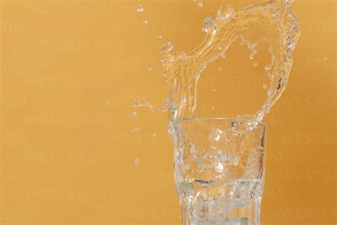 Water Being Poured Into Glass Spilling Over Close Up Stock Photo