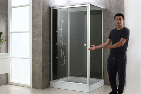 A Man Standing Next To A Shower In A Room With White Walls And Tile Flooring