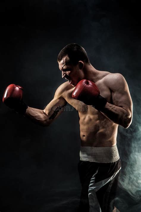 Muscular Kickbox Or Muay Thai Fighter Punching In Smoke Stock Photo