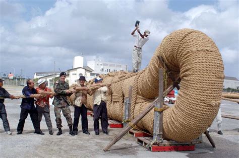 A Group Of Men Standing Around A Large Rope