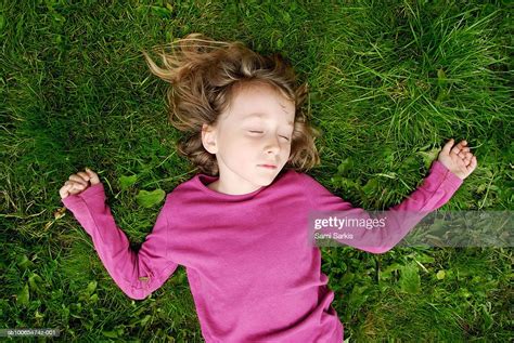 Girl Lying Down In Grass With Eyes Closed Overhead View High Res Stock