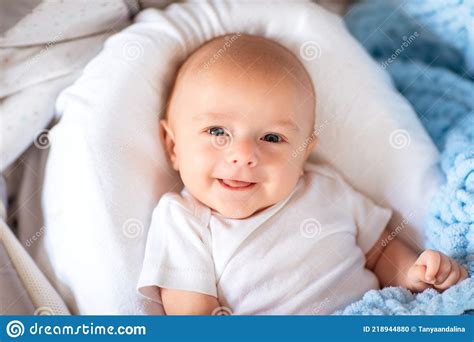 Newborn Baby Boy In White Body Laying In His Cradle With Soft Blue