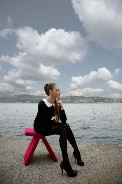 Frau Sitzt Auf Einem Rosa Stuhl Am Strand Kostenlose Foto