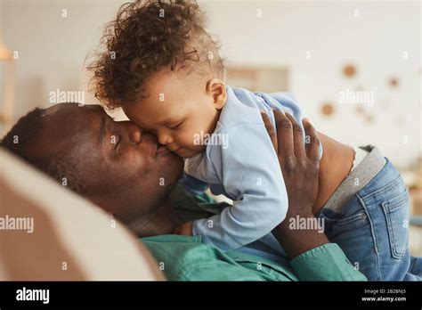 Side View Portrait Of Loving African American Dad Kissing Baby Son