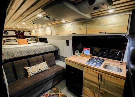The Interior Of A Camper With A Bed Sink And Stove
