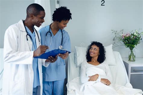 Male And Female Doctors Interacting With Female Patient In The Ward