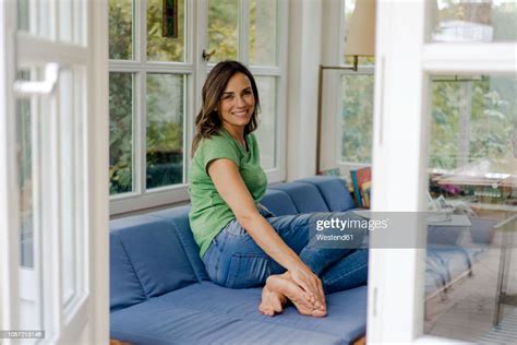 Smiling Mature Woman Sitting On Couch At Home Photo Getty Images