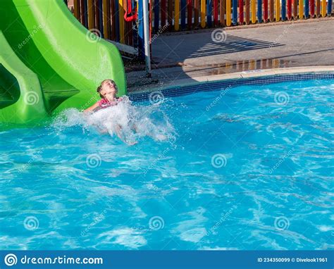 A Beautiful Little Girl Is Riding A Water Slide In The Water Park