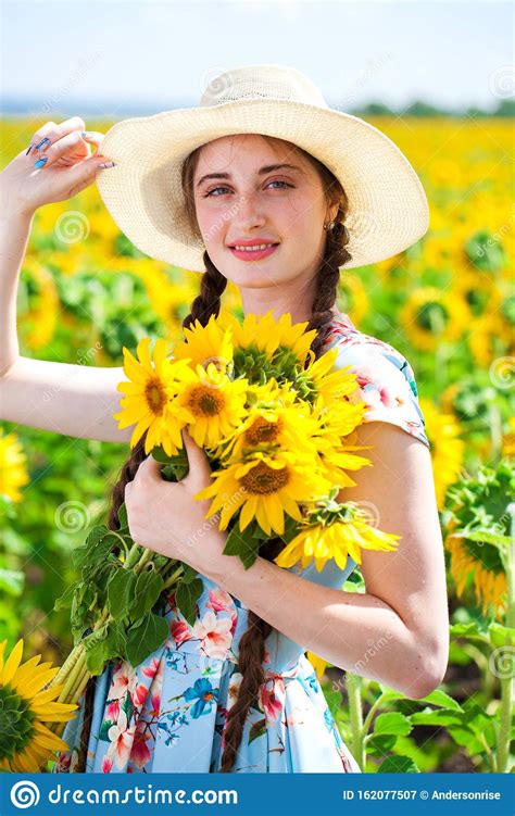 Young Beautiful Woman In A Straw Hat In A Field Of Sunflowers Stock