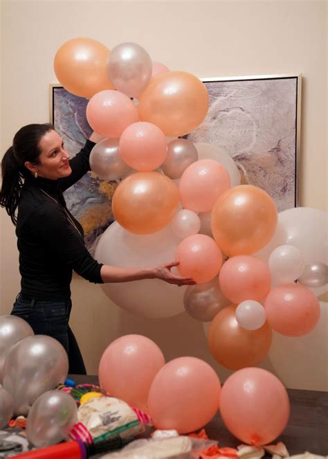 A Woman Is Holding Balloons In Front Of Her Face As She Stands Next To