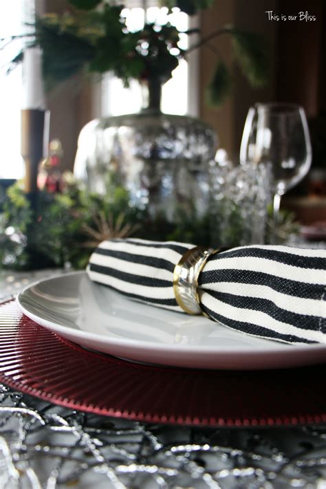 A rustic christmas table setting with a plaid runner, mini christmas trees, red candles in jars, pinecones and colorful napkins. A Christmas Table [Merry, Bright & Blissful Holiday Home ...