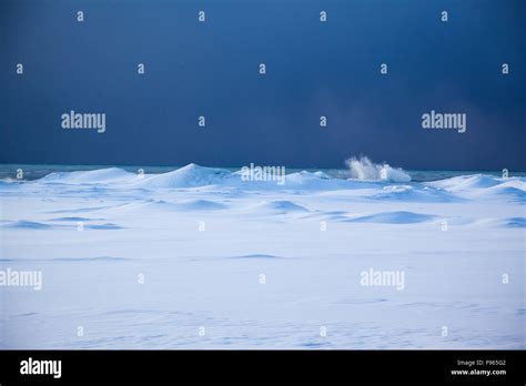 Waves Splash Against The Ice And Snow Covered Shores Of Lake Ontario In