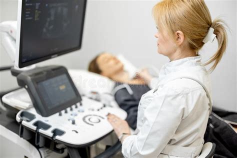 Doctor Examining Thyroid Of Female Patient With Ultrasound Scan In